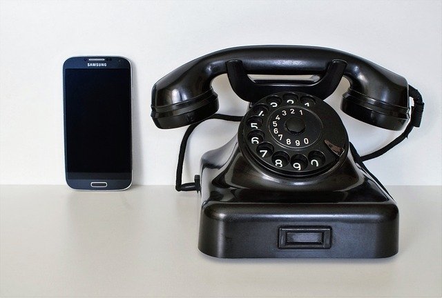 a smartphone next to an old fashioned phone
