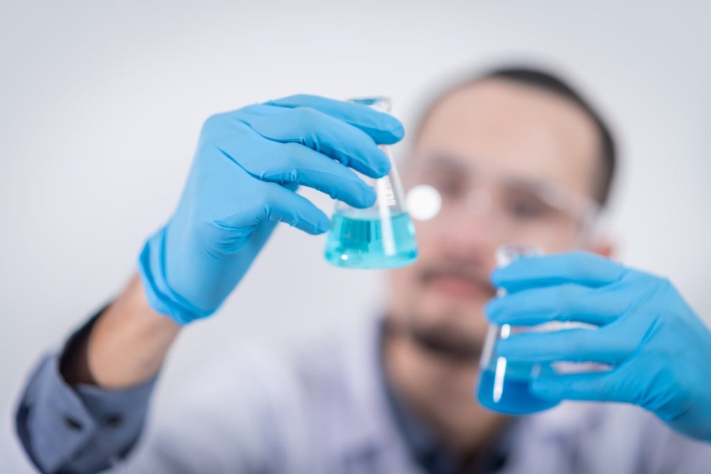 Man looking at two vials of blue liquid