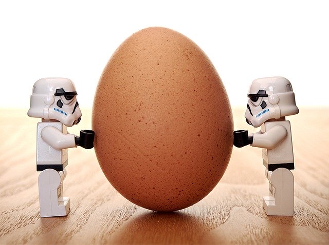 two lego stormtroopers pushing on opposite sides of an egg